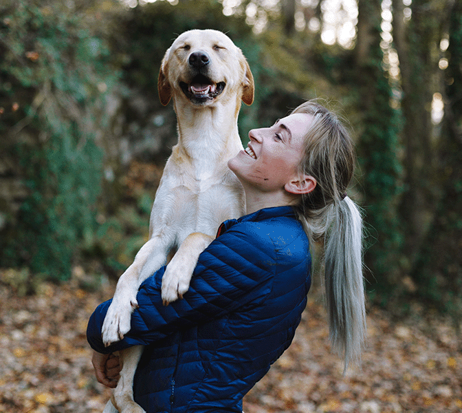 A calm picture of an sporty woman with a happy dog enjoying a day in nature